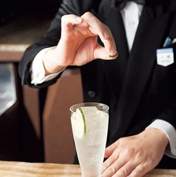 グラスの上で、皮を折ってライムの香りをカクテルに移す。飲む直前に、人前で見せるとよい演出にも。