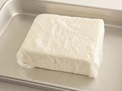 豆腐はべーパータオルで包み、水きりをする。こうすることで焼くときにくずれにくくなる