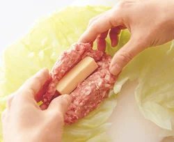 肉だねは、平たく広げてチーズを包んでから、キャベツで包みやすいように俵形にまとめる。