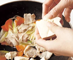 豆腐は手で一口大にちぎって加える。こうすることで、豆腐に味がしみこみやすくなる。