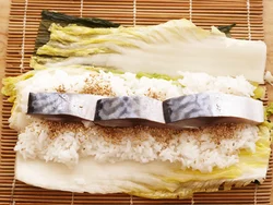 野沢菜漬け、白菜漬け、ご飯、しめさばの順に巻きすにのせる。のり巻きの板のりに当たる白菜漬けは、大きめの葉２枚を重ねて、板のりサイズに。