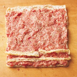 油揚げを開いたときに切り落とした端の部分も肉だねの上にのせて、一緒にくるくると巻けば、むだにせず食べられる。