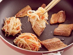 あじを皮目を下にして並べ、小麦粉をつなぎにしたじゃがいもとにんじんをのせて焼く