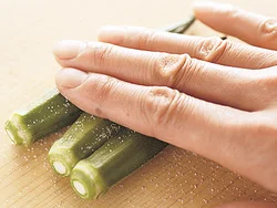 まな板の上で塩をふり、手でまな板にこすりつけるように転がし、うぶ毛を取り除く。食感がよくなり、色が鮮やかにゆで上がる