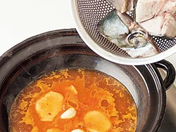 煮汁は煮立たせて酒のアルコール分をとばしたところに、ぶりを加える。