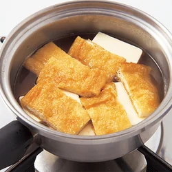 豆腐の上に油揚げをのせるようにして煮ると、落としぶたのような効果で、少ない煮汁でも豆腐に味がしみやすくなる。油揚げは油抜きせずに使うことで、煮汁にコクが出る。