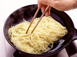 麺をすぐにほぐそうとすると切れるので、１分待って菜箸で少しずつほぐしながら炒める。