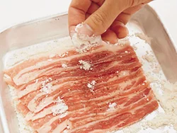 肉がはがれないように小麦粉はしっかりまぶす。またこれによりうまみも閉じ込められる。