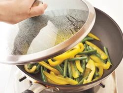 いんげんとパプリカを炒めたら、水を加えて蒸し焼きにすると、火を通す時間を短縮できる。