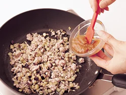 なすとひき肉を炒め合わせ、肉のうまみをなすに吸わせたところに、合わせ調味料を加える。
