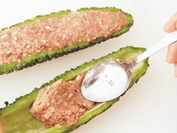 すき間のないよう、スプーンで肉だねを押すように詰める。わたは苦みのもとになるので、事前にしっかり除いて。