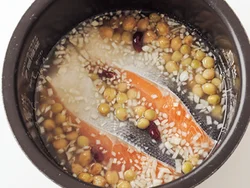 炊飯器に鮭とミックスビーンズを入れるとき、むらなく火が通るように、重ねずに入れる。