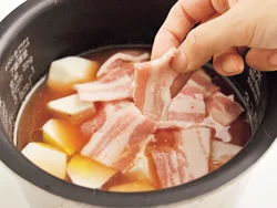 米の上に里いもをのせ、さらに肉を全体をおおうように広げてのせると、肉のうまみがしみこむ。