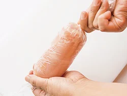 ラップの手前にとり肉を置いてくるくると巻き、両端をねじって結ぶ。