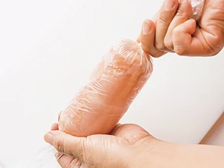 ラップの手前にとり肉を置いてくるくると巻き、両端をねじって結ぶ。