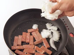 ランチョンミートに焼き色がついたら、先に火の通りにくい白菜の軸と長ねぎを加えて炒める。