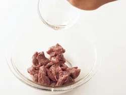 下味と片栗粉をもみ込んだ肉に油をからめると、うまみが逃げず、炒めるときにほぐれやすい。