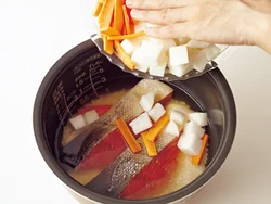 炊飯器に米を入れて水加減したら、鮭、野菜の順に入れ、米にうまみがしみこみやすいようにする。
