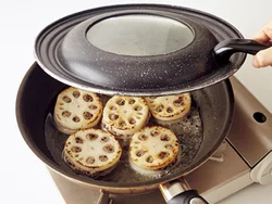 れんこんの両面に焼き色をつけたら水を加えてふたをし、蒸し焼きにして中まで火を通す。