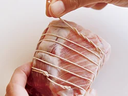 豚肉にネットがない場合、半分に切ってたこ糸を結んでから５㎜間隔で巻き、最後は糸にねじりつける。