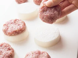 片栗粉をふった大根の上に肉だねをのせ、潰して平らにすると安定しやすい。