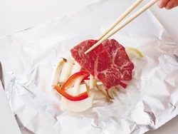 アルミホイルに野菜を広げてのせ、おおうように肉をのせると、肉のうまみが野菜にしみる。
