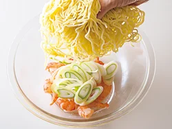 とり肉の蒸し汁に具と麺を加えて加熱