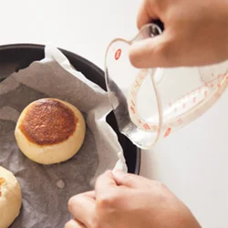 蒸し焼きにするときは、おやきが水につからないよう注意しながら、オーブン用ペーパーの下に水を注ぐ。