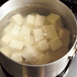 豆腐はおもしをして水きりすると中までかたくなってしまうので、まわりの水けを吸わせるくらいでOK。ゆでることで中はふるふるのまま、まわりは固まってくずれにくくなる。