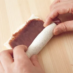 パンに薄くあんをぬり、手前からしっかりと巻いて。あんはパンの縁より少し内側にぬると、巻いたときにはみ出ない。