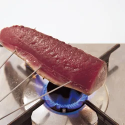皮目から直火に当てて焼くと、かつおの脂が落ちてくる。コンロが汚れるのが嫌なら、焼き網にのせて同様に焼いてもよい。