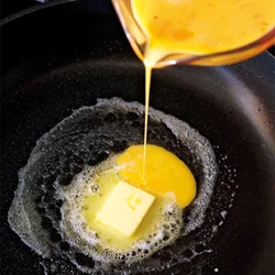 バターが全部溶けないうちに卵液を加え、生のバターの風味を卵に溶け込ませる。このような多めの卵液の分量なら、直径20～22cmのフライパンで焼くと、卵に火がうまく通り、失敗が少ない。