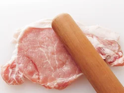 肉は、めん棒などでたたいて薄くのばす。こうすることで、揚げたときに肉がやわらかくなる。