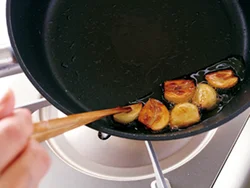 弱火でにんにくを焼いて油に香りを移す。この油で豚肉を焼くことで肉にもにんにくの風味がつく。