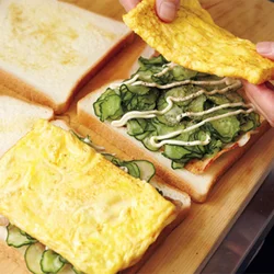 卵焼き器でオムレツを焼くと、ちょうどパンに合うサイズになる。こちらもきゅうりは水が出るので、まん中にくるように具を重ねて。