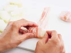 豚肉１枚を縦長に広げ、手前にとうがん１切れを置き、全体を包むようにらせん状にクルクル巻く。