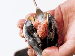 肉だねは小さめのスプーンで少量ずつ、空気を抜きながら詰めていく。なすの断面に小麦粉をまぶしてあるので、はがれにくい。