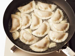 先に餃子とにんにくを入れてから油を注ぐようにすると、はねることもなく、均一に熱が広がる。ガーリックオイルを作りながらそのオイルで揚げる。