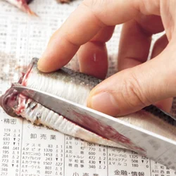 頭のほうから尾のほうに向けて、三角に切り落とし、そこから内臓をかき出す。まな板に新聞紙を敷いて行なうと後始末が楽に。