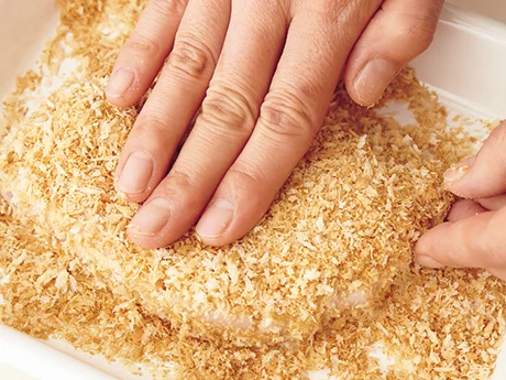 蒸し焼きにした豚肉に水溶き小麦粉を薄くぬり、いったパン粉をまぶす。側面までしっかりと手で押しつける。