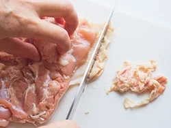 肉の間にある余分な脂を包丁でこそげ取る。とり肉１枚に対して、約20gもの脂が取れ、大幅カロリーダウンに。