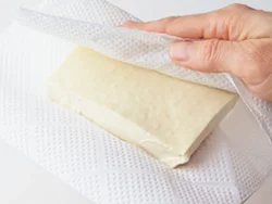 もめん豆腐を使えば水きりの必要なし。ペーパータオルではさんで水けをよく拭き取って。