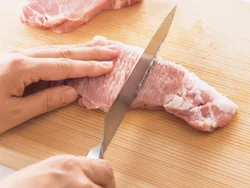 豚肉は両面を包丁の背でたたいてのばす。火の通りが早くなり、やわらかく仕上がる。