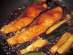 小麦粉をまぶして焼いたサーモンにめんつゆだれをかけながら、たれがとろりとするまでまんべんなく煮からめていく。