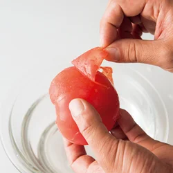 凍らせたトマトをさっと水につけ、皮をむく。湯むきのようにスルッとむける。