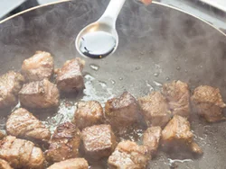 牛肉は転がしながら焼き、全面に焼き色がついたらしょうゆをたらしてこうばしくする。