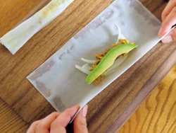 半分に切った春巻きの皮の中央に具材を横長にのせて巻く。両端は押さえて、平たくして留める。