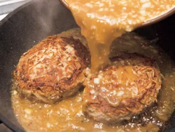 ハンバーグだねを両面こんがりと焼きつけたら煮汁を加える。ふたをして蒸し煮にするので、完全に火が入っていなくても大丈夫。