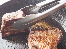 牛肉はトングでつかんで側面も含め、全面を焼く。中まで火が通っているほうがいい場合は弱火でじっくり焼いて。