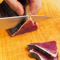 かつおは焼いたらすぐに切り、火が入り過ぎるのを防ぐ。
